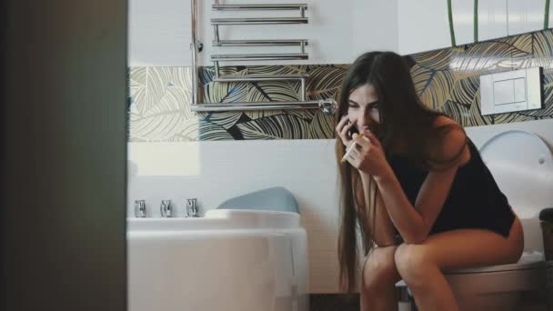 Brunette fille assise sur les toilettes parler au téléphone. Fumer cigarette électronique . — Video