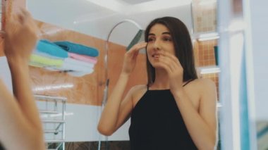 Genç esmer kız banyoda ayna arıyor. Diş kontrol. Yüz. Poz