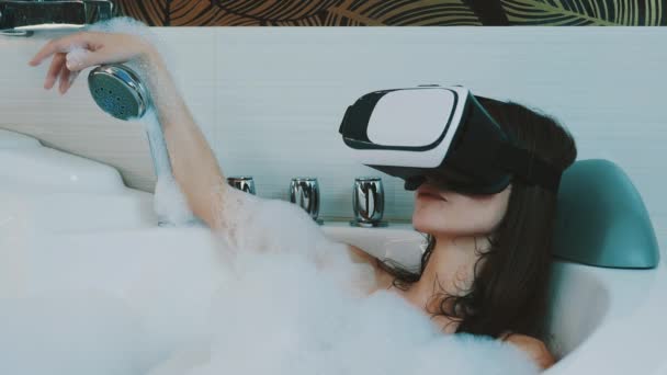 Chica tomar baño lleno de espuma viendo vídeo erótico en gafas de realidad virtual . — Vídeos de Stock