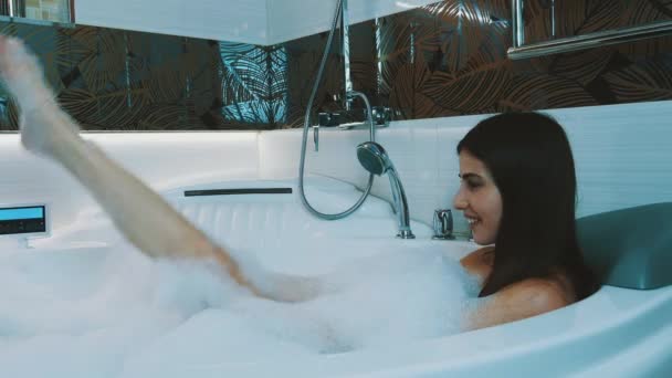 Счастливая девушка принимает ванну, полную пены в ванной. Расслабляюсь. Мыльная пена . — стоковое видео