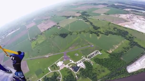 Professionella fallskärmshoppare Fallskärmshoppning i blå himmel ovanför gröna flatland och floden. — Stockvideo