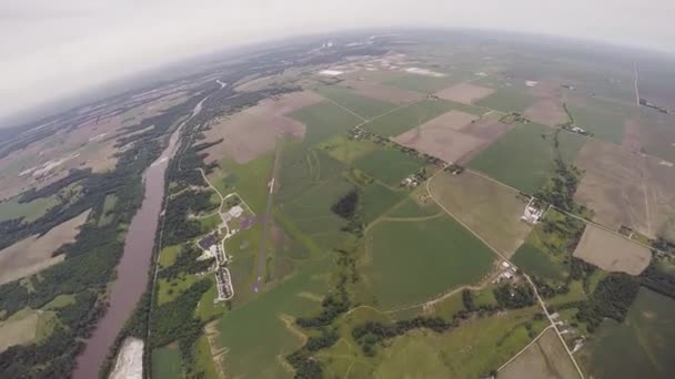 Professional skydiver parachuting in grey heavy sky above green flatland. Sport — Stock Video