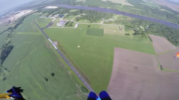 Професійні парашутисти в блакитному небі над зеленими полями. Ландшафтний . — стокове відео