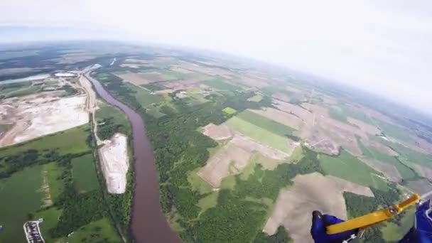 Professionele skydiver parachutespringen in blauwe hemel boven bos en rivier. Landschap — Stockvideo