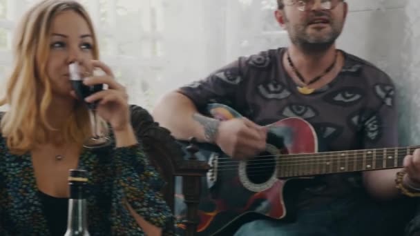 Man oyun gitar kır evi terasta. Kız şarap içeriz. Arkadaşlar masada — Stok video