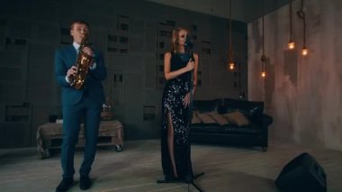Parlayan elbiseli caz vokalisti saksofoncu ile sahne alanı'nda gerçekleştirin. Canlı konser