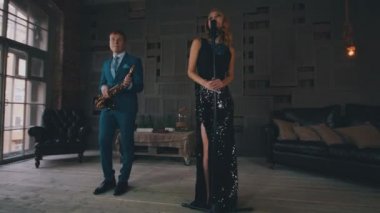 Caz vokalisti parlayan elbiseli mavi kostüm saksofoncu ile sahne alanı'nda gerçekleştirmek