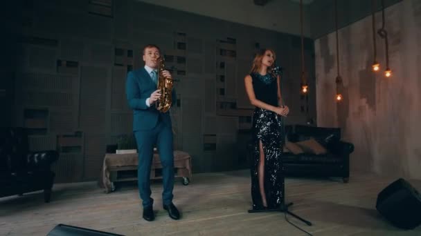 Vocalista de jazz en vestido negro brillante actuando en el escenario con saxofonista . — Vídeo de stock