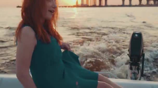 Menina em vestido turquesa sentado no barco a motor. Desfrute de belo pôr do sol . — Vídeo de Stock