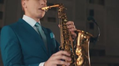 Mavi elbiseli saksofoncu aşamada altın saksafon caz oynamak. Müzik. Sanatçı