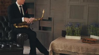 Akşam yemeği ile altın saksafon iskemlede ceketli saksofoncu. Caz sanatçısı