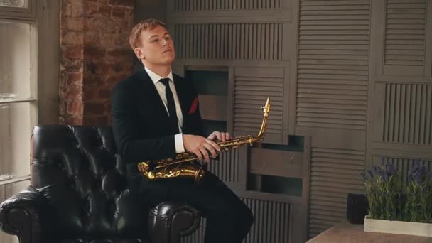 Saxofonista v smoking stojí na jevišti s zlatý saxofon. Jazzový umělec. — Stock video