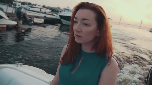 Atractiva chica de pelo rojo en vestido turquesa en barco a motor. Noche de verano. Muelle — Vídeos de Stock