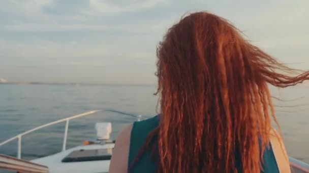Back side of girl in turquoise dress steer motor boat. Beautiful sunset. Driver — Stock Video
