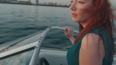 Kızıl saçlı kız turkuaz elbiseyi sürücü Motorlu tekne. Yaz gecesi. Romantik