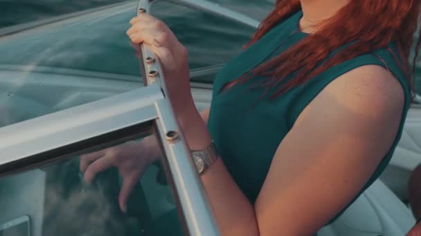 Red hair girl in turquoise dress drive motor boat. Summer sunset. Entertainment. — Stock Video