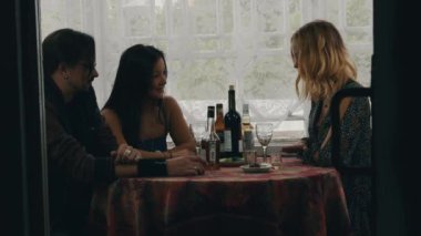 İki genç kız ve adam masada ülke evde alkollü içecekler ile sohbet