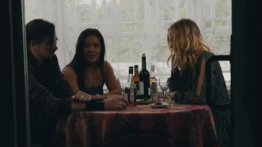 İki kız ve adam masada ülkenin evin terasında içki ile sohbet. Gülmek