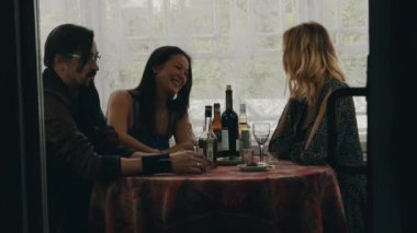 İki kız ve adam masada ülkenin evin terasında içki ile sohbet. Mutlu