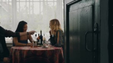 İki kız ve masada konuşan adam. İçki şarap ülkenin evin terasında.