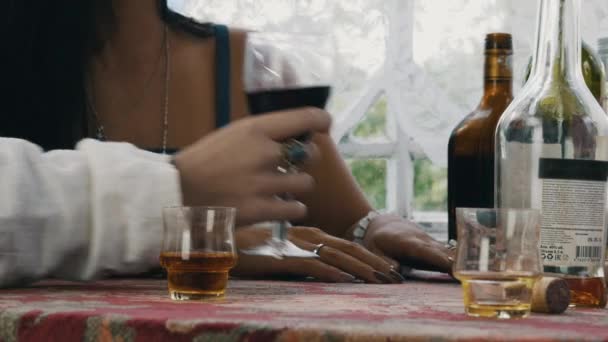 Mädchen sitzen auf der Terrasse im Haus am Tisch. Mann nimmt Glas mit Wein, gibt Wasser zurück — Stockvideo