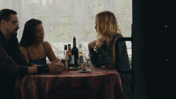 Flicka chatt med par på bordet med drycker på terrassen i hus på landet. Vänner — Stockvideo