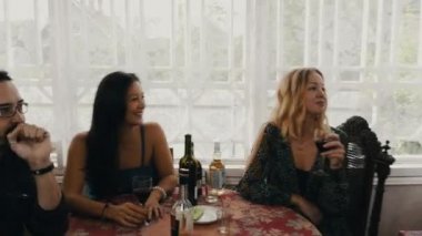 Arkadaşlar ülkenin evin terasında masada şarap içmek. Adam kapı pencere.