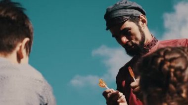 Kırmızı tişörtlü adam sokakta kırsal horoz şeker çocuklar verecektir. Oynarken