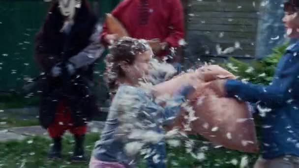 Kinderen vechten kussens in tuin van een landhuis. Vele vliegende veren. Entertainment — Stockvideo