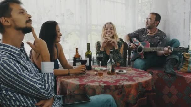Vrienden hebben rest in landhuis aan tafel met drankjes. Man spelen gitaar. — Stockvideo