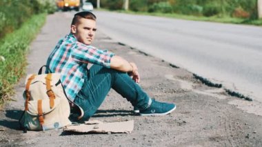 Adam oturup Road kırsal kesimde. Otostop. Yardım bekliyor. Smartphone al