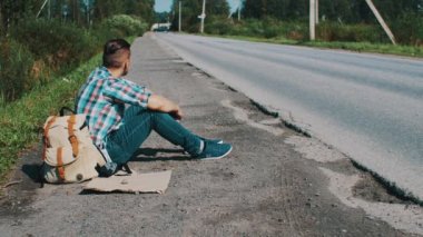 Adam oturup Road kırsal kesimde. Otostop. Yardım bekliyor. Telefonu aç.