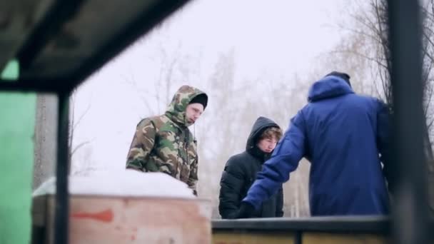 克拉斯诺雅斯克，俄罗斯-2014 年 3 月 15 日︰ 几名年轻男子在街上呆在冬天。想要的东西的雪下。朋友。友谊. — 图库视频影像