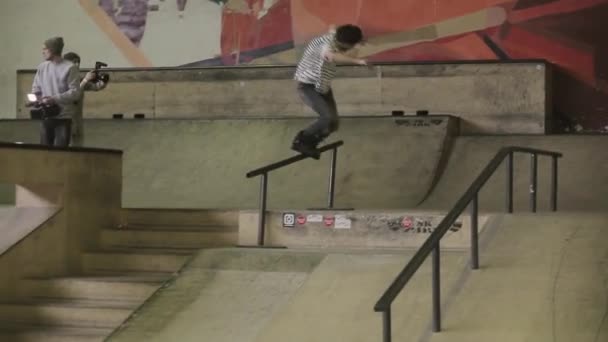 KRASNOYARSK, RUSIA - 15 DE MARZO DE 2014: Un joven patinador de patinaje sobre ruedas da la vuelta a la valla en el skatepark. Desafío. Camarógrafo en rodillos — Vídeo de stock