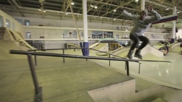 KRASNOYARSK, RUSIA - 15 DE MARZO DE 2014: Patinador en sombrero gris hacer resbalón en la valla, diapositiva en el trampolín en skatepark. Competencia . — Vídeos de Stock