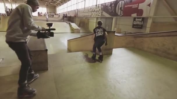 KRASNOYARSK, RUSIA - 15 DE MARZO DE 2014: El patinador patinador hace un deslizamiento trasero extremo en el trampolín en el skatepark. Camarógrafo en rodillos. Competencia — Vídeo de stock