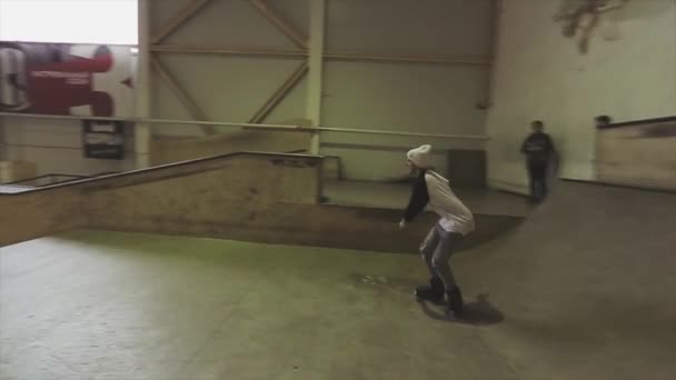 KRASNOYARSK, RUSIA - 15 DE MARZO DE 2014: Patinador de patines con gorro blanco rueda en el borde del trampolín en competición en skatepark. Desafío — Vídeo de stock