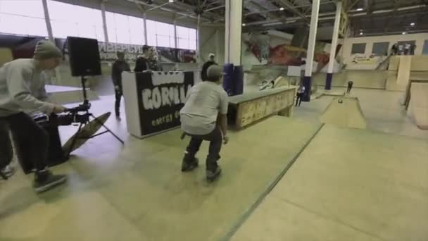 KRASNOYARSK, RÚSSIA - 15 de março de 2014: Patinador de patins salta de um trampolim sobre outro. Golpe extremo. Competição no parque de skate. Cameraman — Vídeo de Stock