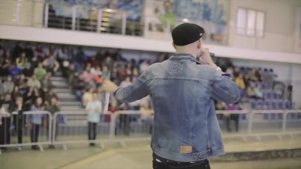 KRASNOYARSK, RUSIA - 15 DE MARZO DE 2014: La parte trasera del hombre con sombrero habla en micrófono con la gente en el parque de skate. Desafío. Competencia. Hostia — Vídeos de Stock