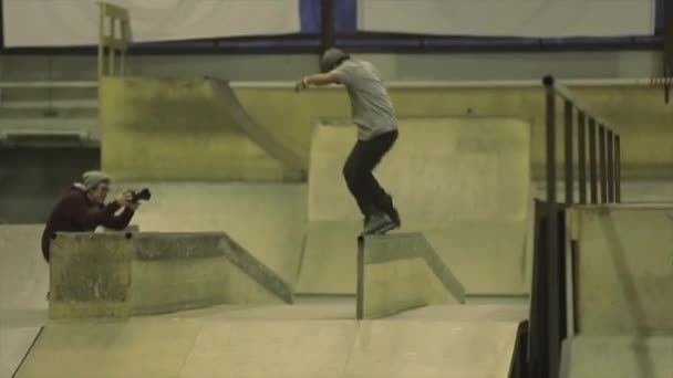 KRASNOYARSK, RUSIA - 15 DE MARZO DE 2014: Rodillo de patinador sobre valla con pies cruzados. Un trampolín. Extremadamente. Camarógrafo. Competencia en skatepark — Vídeo de stock