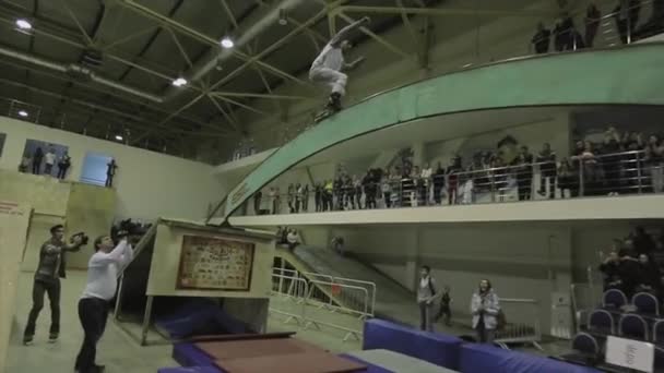 KRASNOYARSK, RUSIA - 15 DE MARZO DE 2014: Rodillo de skater moler en arco curvo entre trampolines. Camarógrafo. Gente. Competencia en skatepark — Vídeo de stock