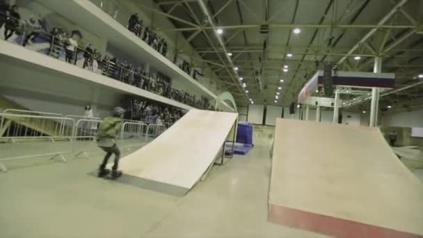 Krasnoyarsk, Ryssland-15 mars 2014: rullskridskoåkare i hjälm rulle på båge mellan språngbrädor, faller på Mats. Tävling i Skate Park — Stockvideo