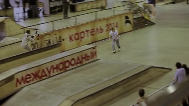 Krasnojarsk, russland - 15. März 2014: Junge Rollschuhläuferin rutscht auf Zaun, kreuzt Füße. Kameramann bewegt sich für ihn. Wettbewerb im Skatepark — Stockvideo