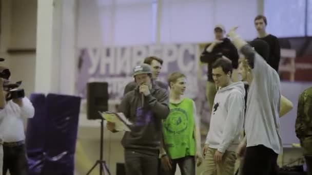 KRASNOYARSK, RÚSSIA - Março 15, 2014: Jovem anfitrião em cap falar em microfone no palco. Patinadores. Cameraman. Competição no parque de skate — Vídeo de Stock