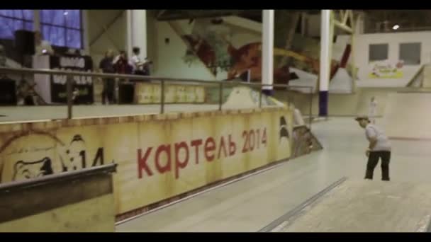 KRASNOYARSK, RUSIA - 15 DE MARZO DE 2014: Rodillos de patinador en la valla con los pies cruzados delante de la cámara. Salta. Competencia en skatepark . — Vídeo de stock