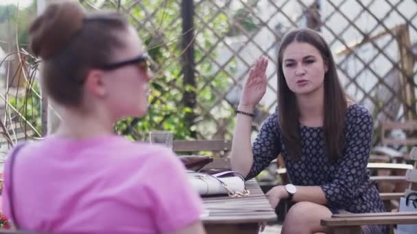 Chicas jóvenes se sientan en la terraza del restaurante . — Vídeos de Stock