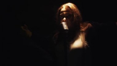 Eldivenli scrubwoman boş kulüp sahnede vintage mikrofona şarkı. Dans