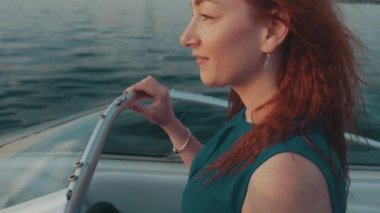 Kızıl saçlı kız turkuaz elbiseyi sürücü Motorlu tekne. Yaz gecesi. Romantik.