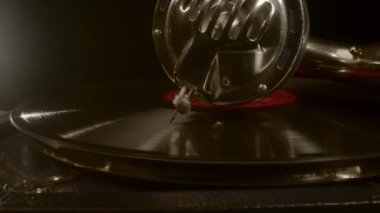 Mans el, vinil plaktan müzik çalan bir gramofonun mekanizmasını başlatır.