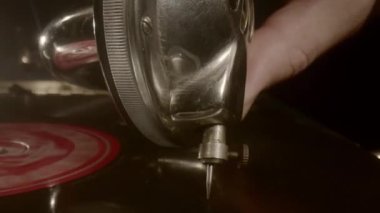 Bir adamın eli eski bir gramofonun vinil plağına iğne batırır..